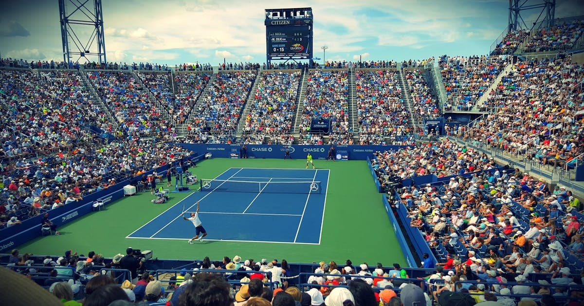 Spettatori seguono una partita di tennis dagli spalti, a rappresentare una partecipazione inclusiva