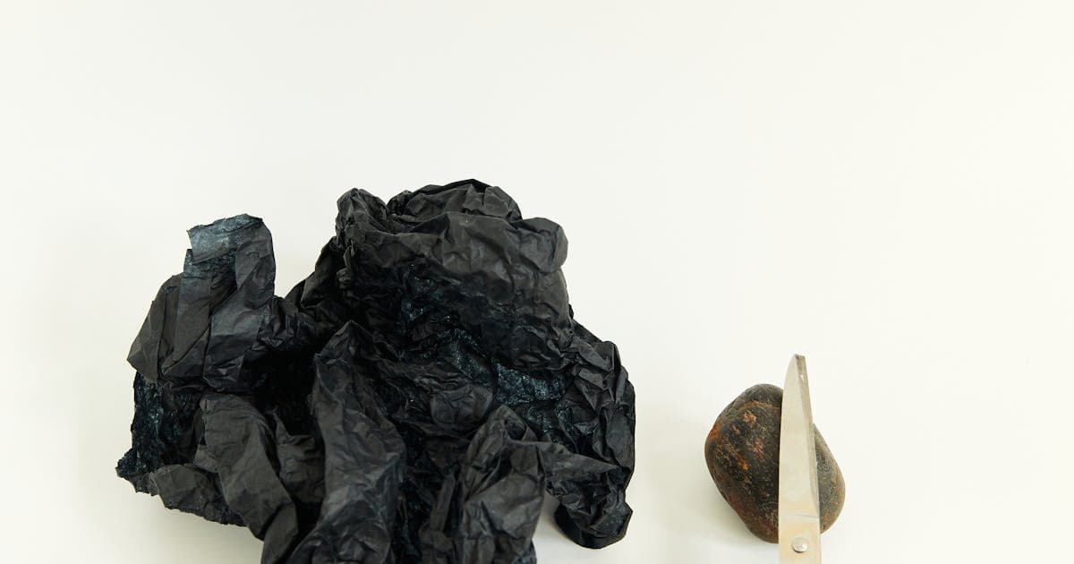 Künstlerisches Stillleben mit Stein, Papier und Schere auf weißer Oberfläche